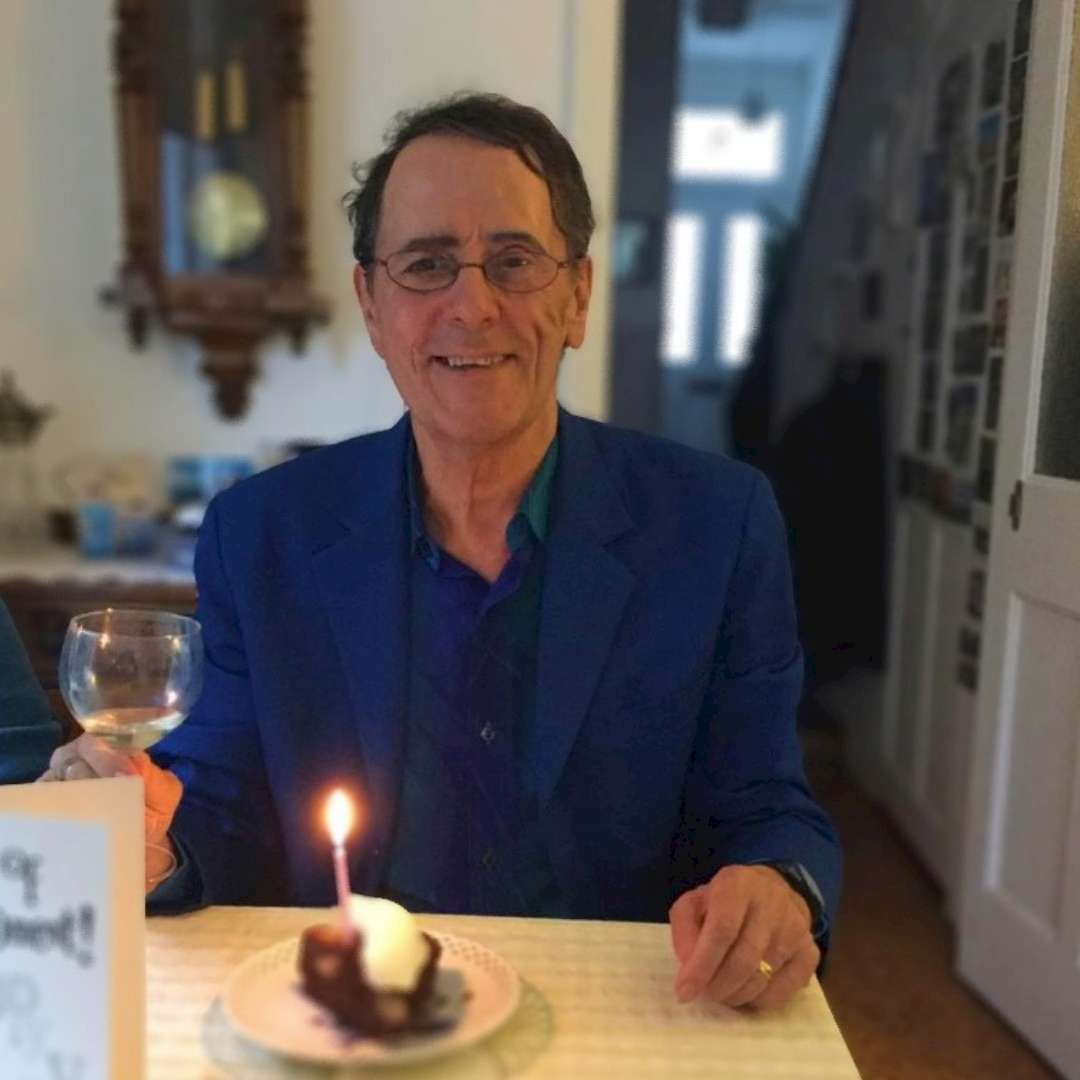 Dugan sat at a table with a glass of wine and a cake with a candle.
